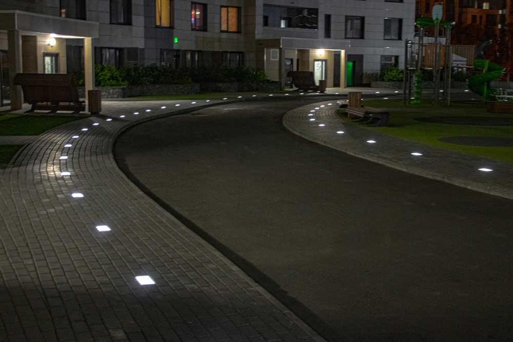 На фотографии тротуарная плитка светится для удобства пешеходов